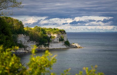 View of the cliffs covered with green vegetation against the blue sea and cloudy sky. Stevns Klint.