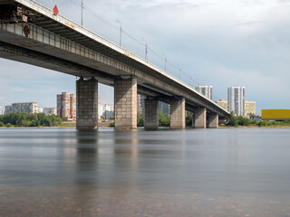 Bridge across the wide river against cityscape