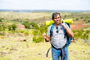 Excited happy middle aged man talking on mobile phone call during trekking on top of hill - concept of connection, technology and communication.