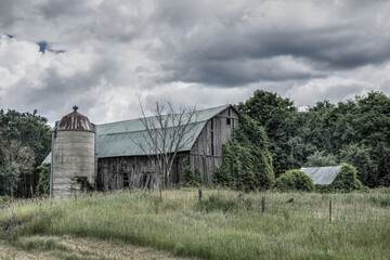Fototapeta na wymiar Old dilapidated wooden barn in a farm field
