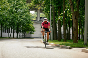 Man in sunglasses speeds along the road against a background of summer park. Man with a bicycle hobby rides in the park.