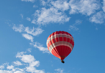 A large balloon is flying over a cloudy blue sky