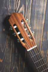 Close up neck of the guitar..Brown colored wooden guitar on the wooden background. Musical...