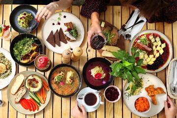 People eating a lunch together, top view. Enjoying dinner, sharing dishes with friends. Vegan friendly restaurant. 