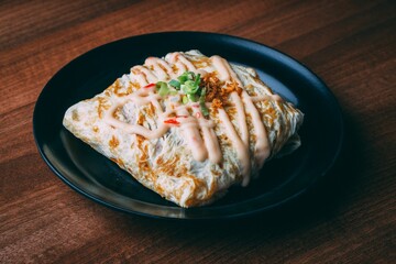 Plate of freshly made dish - a flatbread with filling and mayochup sauce topping