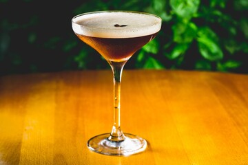 Glass cup of espresso martini cocktail on a wooden table