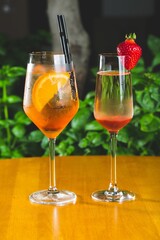 Glass cup of Aperol and Spritz Veneziano cocktails on a wooden table