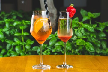 Glass cup of Aperol and Spritz Veneziano cocktails on a wooden table