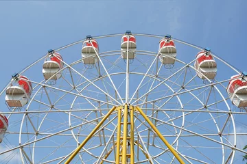 Foto op Plexiglas carnival, Ferris wheel over blue sky in amusement park in summer © Artoniumw