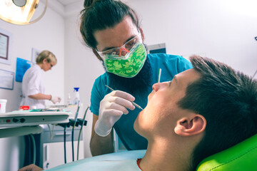 Closeup image of bearded dentist checking up patient boy's teeth in dentistry clinic.