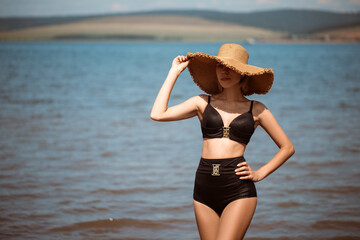 Sexy girl in a wide hat with a pug on the beach