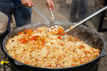 Stirring the pilaf in a large bowl during cooking outdoors.