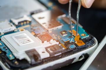 Technician repairing inside of mobile phone by soldering iron. Integrated Circuit. the concept of...