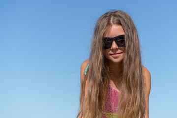 Portrait of a girl in sunglasses against the blue sky.