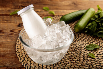 A bottle of AYRAN YOGHURT DRINK served in iced cube bowl side view on grey background