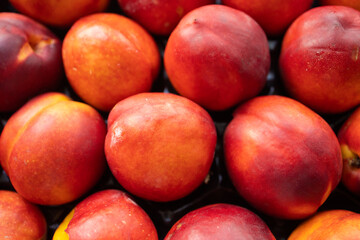 Fototapeta na wymiar ripe, juicy nectarines lie in a box, close up. An energy charge, vitamins, ripe fruits, nectarine cultivation, pesticides. Disruption of fruit supply, import