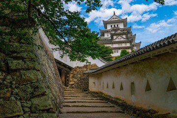 Footpath with stony staircases in background of Himeji castle under blue bright sky