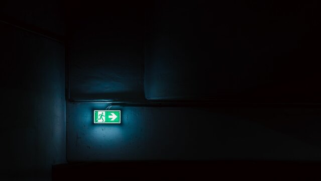 Closeup of a neon emergency exit sign in an underground garage