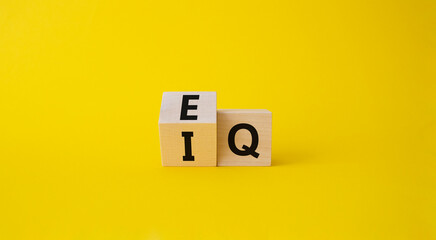 IQ or EQ symbol. Turned cube with words IQ, intelligence quotient to EQ, emotional quotient. Beautiful yellow background. Emotional and intelligence quotient concept. Copy space.