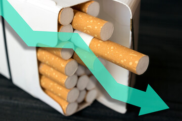 Smoking ban, reducing the number of smokers, raising the age for selling tobacco products. a pack of cigarettes on a black background with a falling graph, cigarette sales are falling