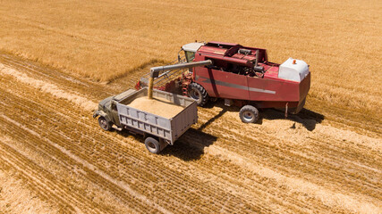 Fototapeta na wymiar Aerial view of Combine Harvester Unloading Wheat Grain Into The Truck