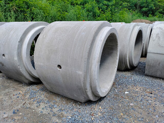 Concrete sewage pipes in the park waiting to be put underground. They are sitting on the crushed stones.