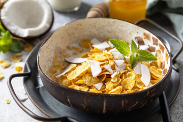 Vegan healthy breakfast. Cereal granola breakfast flakes with coconut non-dairy alternative milk and fresh coconut slices on a stone tabletop.