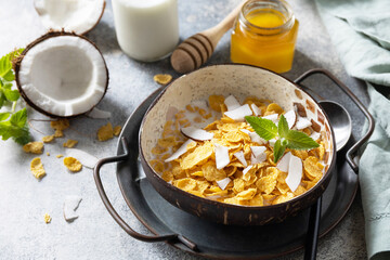 Summer vegan breakfast. Cereal granola breakfast flakes with coconut non-dairy alternative milk and fresh coconut slices on a stone tabletop. Copy space.