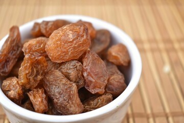 A Selective closeup picture of Dried Munakka or Abjosh in a white Bowl. Dry fruits grown in Afghan