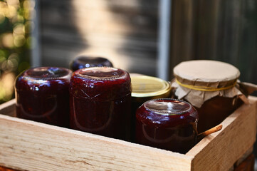 Close-up of wooden crate with homemade berry confiture in jars standing upside down against a wooden rustic background