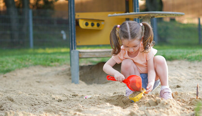 Beautiful baby  having fun on sunny warm summer day - Cute toddler girl playing in sand on outdoor playground