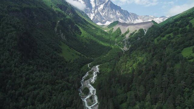 Aerial of curving Baksan river and Cheget mountain, North Caucasus. Picturesque snow capped peaks of Donguz Orun-Cheget-Karabashi in Elbrus region. Breathtaking summer landscape