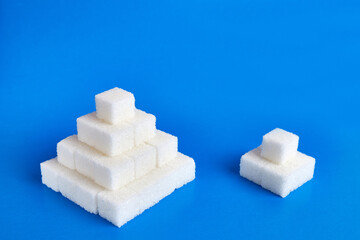 Two pyramids of pressed sugar of different sizes on a blue background. Food crisis concept.