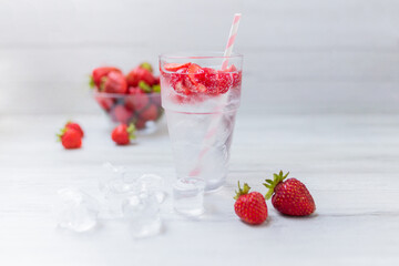 Water with strawberry. Fresh strawberry cocktail. Summer cocktail with strawberry and ice cubes.  Glass of strawberry soda drink on white wooden background.