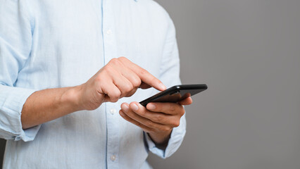 Close-up of unrecognizable man in shirt holding mobile phone, touching smartphone screen with his...