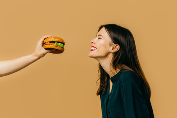 Fast food advertising concept. A girl with a burger on a colored background.