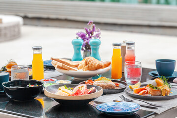 Served breakfast in luxury hotel. Poolside table with various delicious food, freshly squeezed...