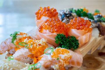 Set of salmon rolls topped with caviar and burned salmon sushi on a wooden tray in japanese...