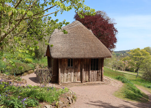 An quaint hut with a thatched roof looks out over the English countryside