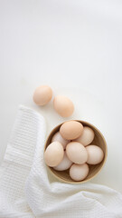 brown chicken eggs on a light plate on a white background