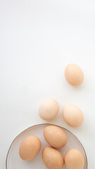 brown chicken eggs on a light plate on a white background