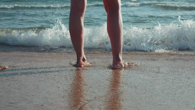 woman's feet hit by a small wave on the seashore
