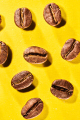 Roasted coffee beans isolated close up on yellow background, clipping path