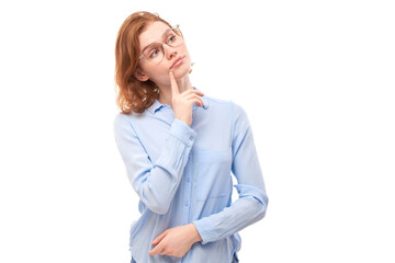 Smart redhead girl in glasses and business shirt holding chin thinks doubts, makes decision isolated on white studio background
