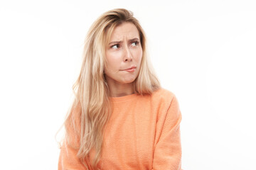 Naklejka premium Smart blonde girl in casual grimacing and biting her lips thinks doubts, makes decision isolated on white studio background