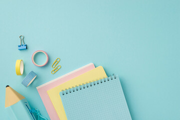 Back to school concept. Top view photo of colorful stationery stack of notebooks pencil-case adhesive tape and binder clips on isolated pastel blue background
