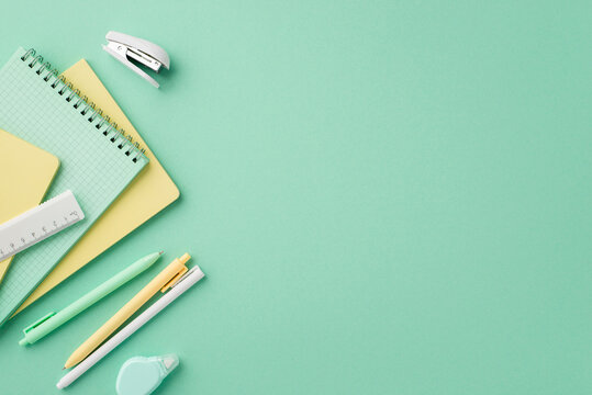 Back to school concept. Top view photo of stationery copybooks pens round correction tape ruler and mini stapler on isolated pastel green background with copyspace