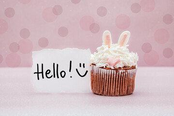 Hello - card with text and smiley face on pink background with bunny cupcake
