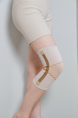 Knee support brace on a woman leg. girl in an orthosis in the interior of the house. Orthopedic...