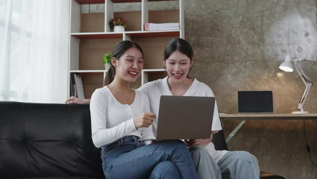 Two women have a video call via laptop on living room. 